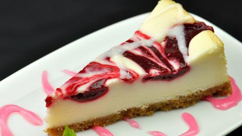 A fork slicing into a piece of cherry cheese cake